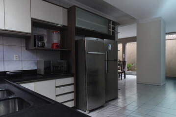 modern kitchen interior with stainless steel appliances, dark countertop and wood cabinets, functional home cooking space,contemporary residential kitchen design, two large refrigerators and integrate