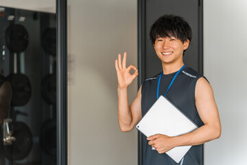 Male gym trainer, personal trainer, and instructor with tablet