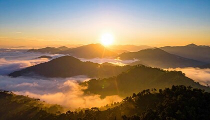 Scenic aerial view of mountain range with clouds at sunrise, bathed in golden light.