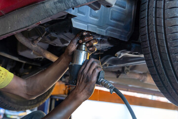 Auto mechanic draining transmission fluid from a vehicle during an ATF or Automatic Transmission Fluid oil change. Automotive maintenance, car repair and service concept.