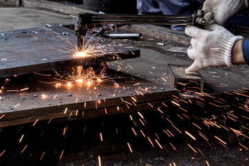 Worker Cutting Steel with Welding Torch and Flying Sparks
