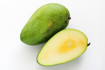 A whole Kiojay mango paired with a freshly cut half, showing its pale yellow flesh against a smooth green skin, set on a clean white background.