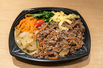 A ready-to-eat beef and vegetable dish featuring ground beef, sliced onions, carrots, tomatoes, and egg strips served on a single plate.