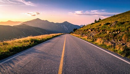 An empty road stretches towards mountains under a colorful sunset sky. The landscape features grassy hills and a clear, open vista.