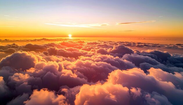A beautiful aerial view of clouds illuminated by the setting sun during the golden hour. The sky transitions from blue to orange.