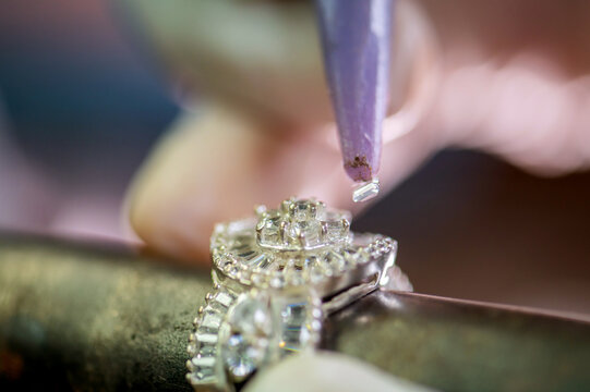 A close up of a jeweler setting a diamond into a ring.