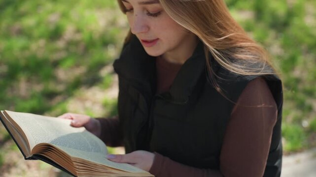 white woman reading book outdoors as asian friend relaxes and scrolls on phone, focused study atmosphere in sunlit park bench subtle tutor style exchange and serene academic energy, pages and gentle