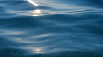 ﻿Extreme close-up slow motion shot of bright sunlight reflections shimmering on the undulating surface of deep blue clean water sunlight reflections, serene, cinematic