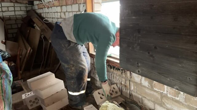 A stove fitter carries bricks onto the roof. Bricks for the chimney. Construction of a heating stove.
