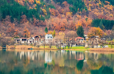 Fototapeta premium Scenic lake view in Herzegovina with cabins, abstract composition emphasizing water reflections and mountain silhouettes
