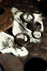 Replacing a wheel bearing in a classic car. Old vehicle restoration concept. Worn wheel bearing on a dirty, oily napkin. Metal textured background.