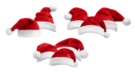 group of traditional red velvet santa claus hats with fluffy white pom-poms and trim clustered tightly together, isolated on black.