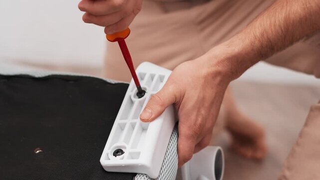 Focused on task, man works on connecting chair components, close up hands using screwdriver to secure each element. Home environment emphasizes practical skills and everyday problem-solving.