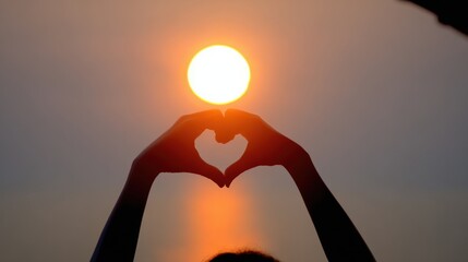 A silhouette of hands forming a heart shape around a rising sun, creating a serene and romantic atmosphere at sunset.