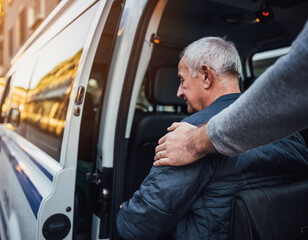 Elderly care concept: A Man’s Hand Touching the Shoulder of an Older Disabled Man in an Ambulance