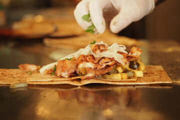 Chef preparing a chicken wrap with fresh toppings 