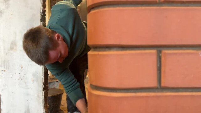 A stove fitter washes the brickwork of a built stove. Construction of a heating stove. Vertical video. Close-up.