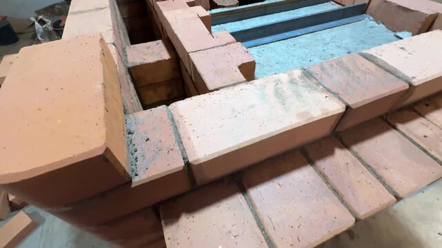 Construction of a heating stove. Demonstration of brickwork from the stove foundation to the firebox ceiling. The fireclay stove core is covered with mineral wool.