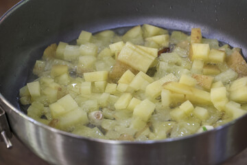 Cooking diced potato and onion in frying pan with sizzling hot oil. homemade food preparation of simple recipe sauteed for comforting and delicious meal