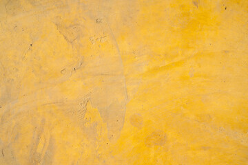 Yellow concrete wall texture, abstract background with rough surface, subtle stains, and weathered appearance, suitable for design, construction, or architectural projects