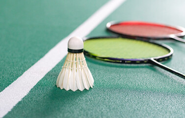 Cream white badminton shuttlecock and racket on floor in indoor badminton court, copy space, soft...