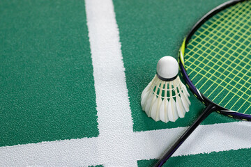 Cream white badminton shuttlecock and racket on floor in indoor badminton court, copy space, soft and selective focus on shuttlecocks.