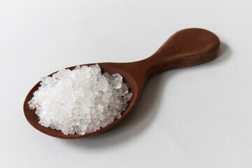 Natural salt in wooden spoon isolated on white, top view