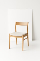 Fototapeta premium Single wooden chair placed in front of blank vertical white poster board isolated on clean pure white studio background