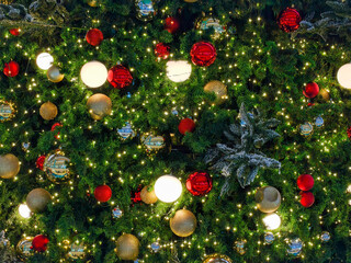 A glowing Christmas tree in the background, adorned with red and gold ornament balls, captures the...