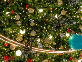 In the background, a glowing Christmas tree decorated with red and gold baubles ornaments and blue...