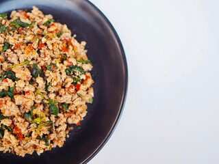 Stir-fried minced pork with basil in a plate placed on a white blackground. Delicious Thai food.