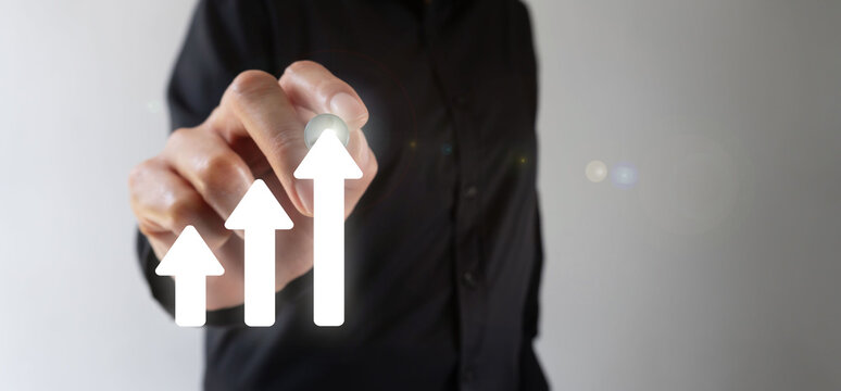 Businessperson pointing forward with a digital pen towards a graph made with upward-pointing arrows