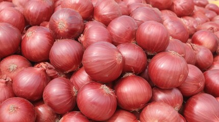 A close-up view of a large pile of fresh, vibrant red onions, ready for sale