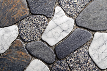 Natural stone floor texture background with polished irregular pebbles in a mosaic pattern. Grey, white, and marble details on a decorative pavement surface for architectural design.