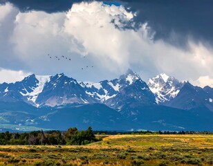 Scenic mountainous landscape under cloudy sky with flying birds