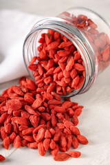 Overturned jar with dried goji berries on white grunge background, closeup