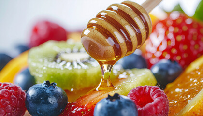 Close-up of honey dripping onto a vibrant fruit salad with various fresh berries.