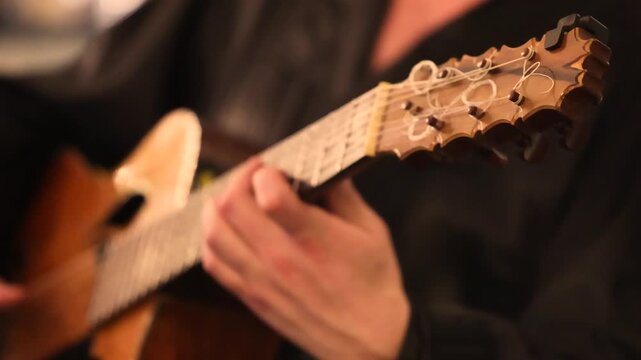Closeup of acoustic guitar strings with hands playing detailed musician performance