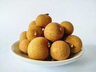 Ripe longan fruits on a white plate with a bright white backdrop, highlighting organic texture and tropical freshness for food and wellness visuals.