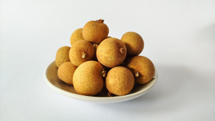 Ripe longan fruits on a white plate with a bright white backdrop, highlighting organic texture and tropical freshness for food and wellness visuals.