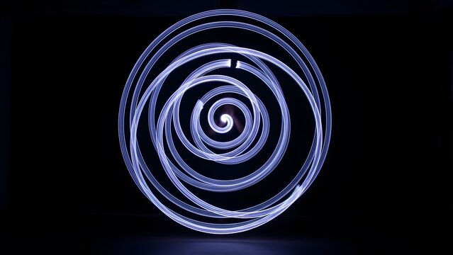 Abstract spiral light painting with glowing blue lines on black background