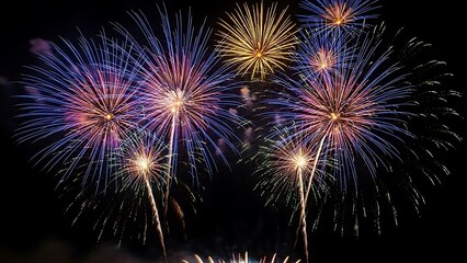 Spectacular multicolored fireworks exploding high above, creating a dazzling display of light against the midnight backdrop