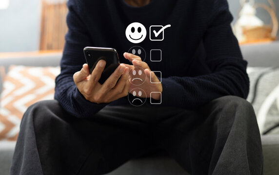 Customer pressing on smartphone with happy icon for feedback review satisfaction service 	
