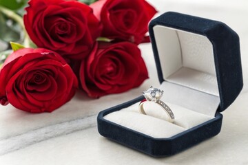 Elegant Engagement Ring in Velvet Box Surrounded by Fresh Red Roses on Marble Surface