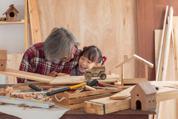 Carpenter family lifestyle activities concept, happy old age grandpa carpentry owner spends time with grandchild on holiday enjoy good relationship hobby and play together with adorable granddaughter