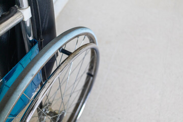 Close-up photo of a wheelchair wheel showing mobility support and accessibility design for people with leg disabilities. Focus on detail and medical care equipment.