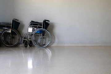 A folding wheelchair placed against a clean hospital wall, ready for patient support and medical service. Minimal, clinical environment suitable for healthcare concepts.