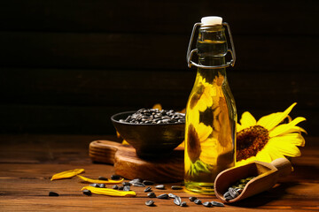 Bottle of sunflower oil and seeds on brown wooden background, closeup