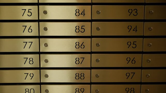 Orderly rows of numbered brass safe deposit boxes inside a secure bank vault, with keyholes and panels forming a precise grid that conveys protection, wealth, and privacy.