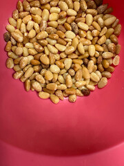 Raw shelled pine nuts in a vibrant pink bowl with ample copy space